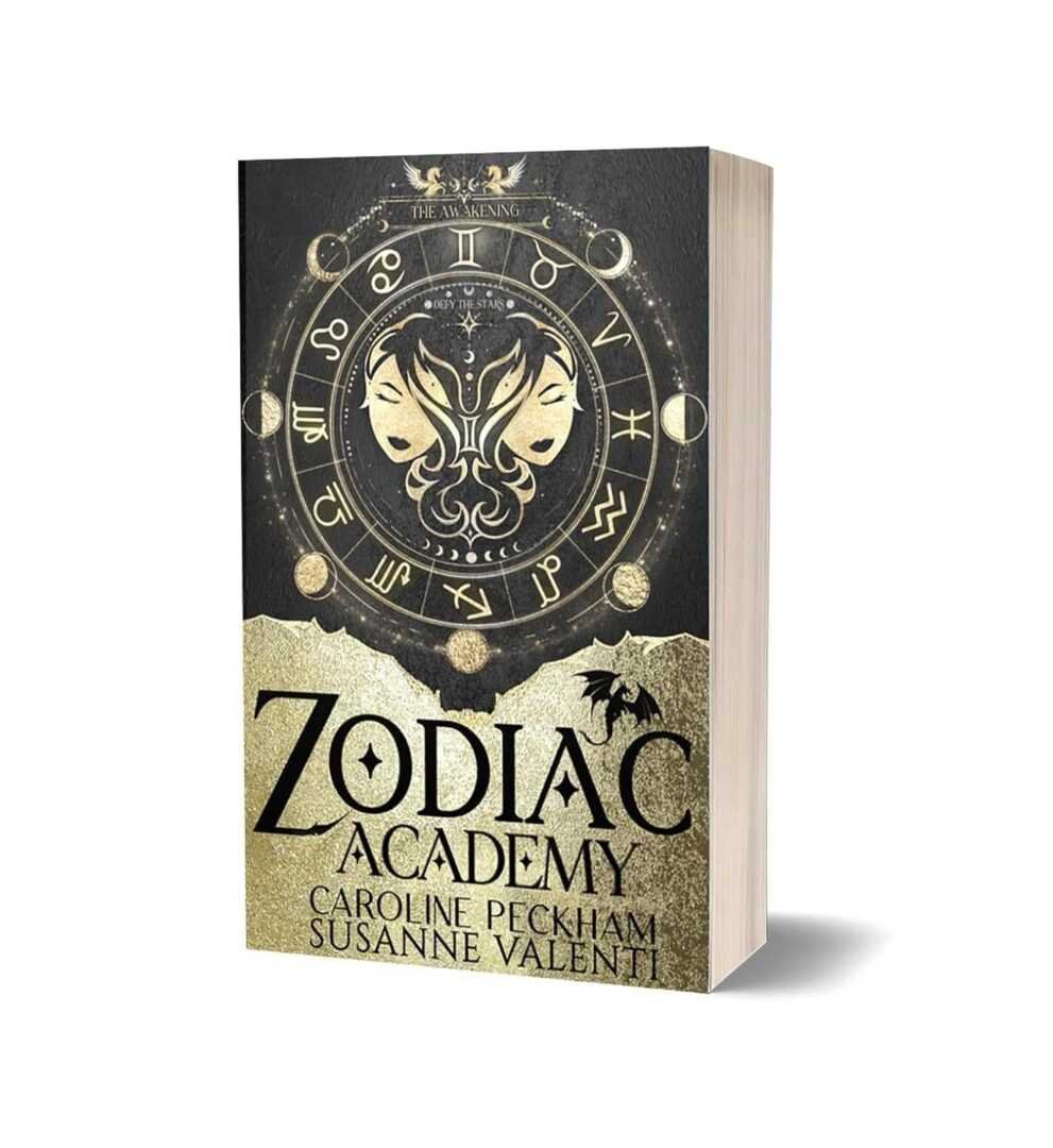Bestselling paperback Zodiac Academy: The Awakening by Caroline Peckham & Susanne Valenti (Zodiac Academy, 1 of 12). A trending BookTok favorite, perfect for romance fans, with a gold and black cover featuring zodiac symbols and twin faces.