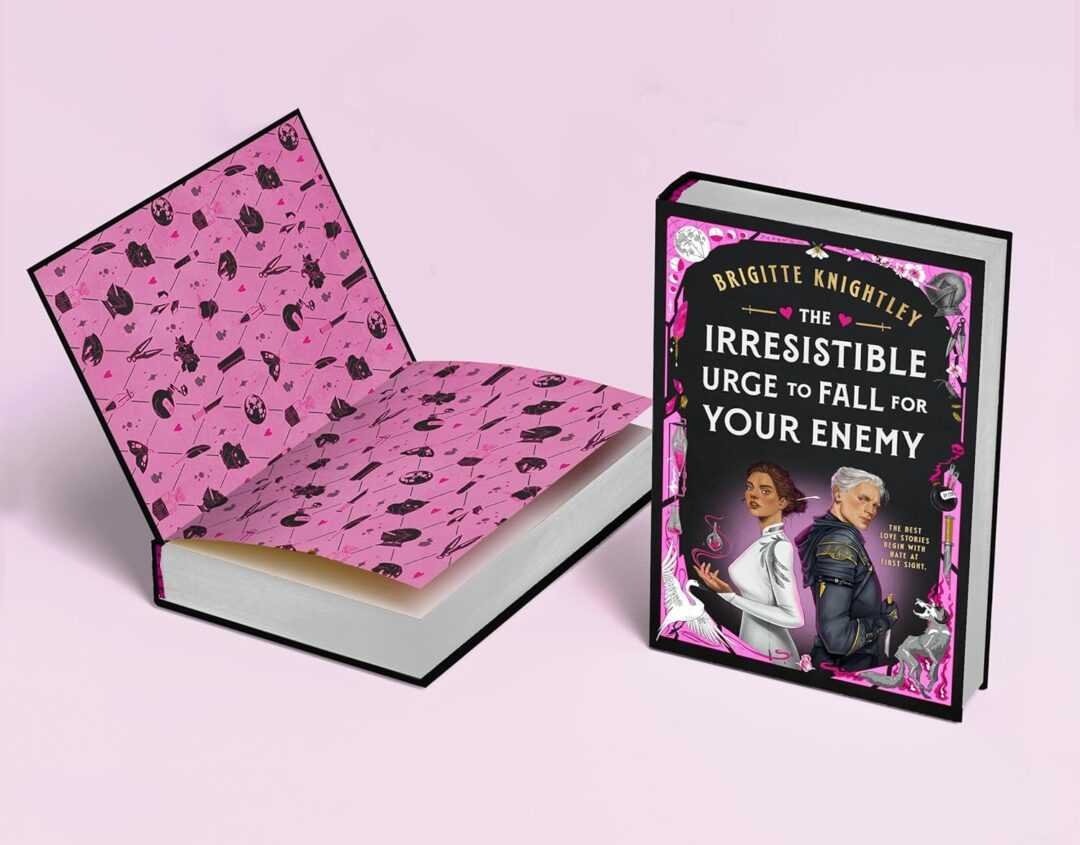 Two hardcover books rest on a pale pink surface; one is open to pink endpapers with black weapons and potions. The other stands upright—it's "The Irresistible Urge to Fall for Your Enemy" by Brigitte Knightley, a contemporary romance novel.