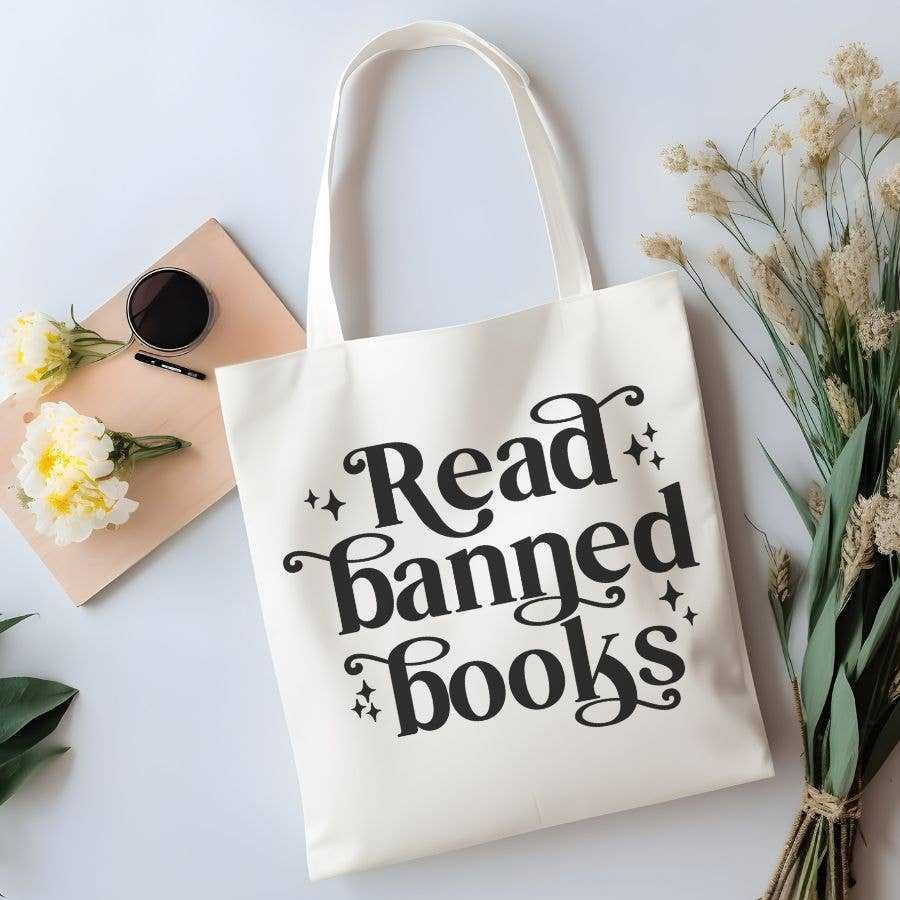 The Read Banned Books Canvas Tote Bag features bold black lettering, floral accents, and space for your essentials—ideal for fans of BookTok trends and contemporary fiction.