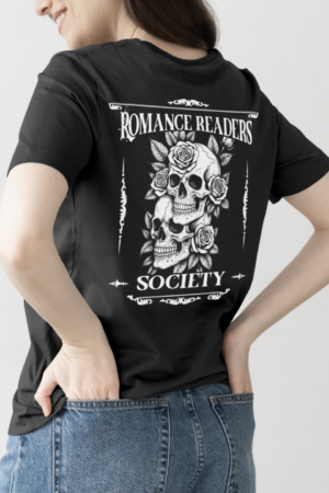 Wearing the black Romance Readers Society Tee with a white graphic of two skulls, roses, and “Romance Readers Society” text on the back, a person stands with one hand in their jean pocket.